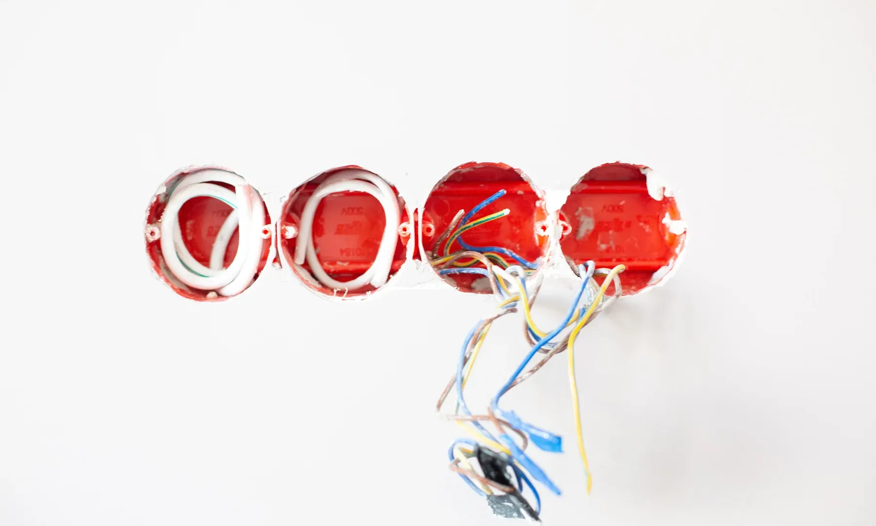 Elektryk Łódź, naprawa instalacji elektrycznej Otwarte puszki elektryczne w ścianie z podłączonymi przewodami instalacji